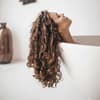 Dicke Haare: Frau liegt in Wanne mit braunen Locken