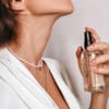Frau besprüht Hals mit Parfum