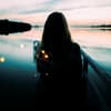 Frau steht am See mit einer Lichterkette