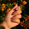 weibliche Hand mit braunem Chrome Nagellack