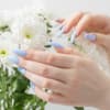 Hände mit hellblauen Nägeln und weiße Blumen Hände mit hellblauen Nägeln und weiße Blumen
