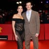 Dua Lipa in einem schwarzen Spitzenkleid und Callum Turner in einem braunen Anzug.