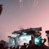 Festival-Bühne bei rosafarbener Dämmerung mit Feuerwerk am Himmel.