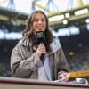 Laura Wontorra ist als Sportmoderatorin nicht mehr wegzudenken und begleitet 2026 die Fußball-WM. Eine junge Frau mit braunen Haaren steht in einem Fußballstadio und moderiert.