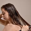 Frau kämmt lange Haare mit Haarmaske