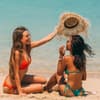 Zwei Frauen sitzen im Bikini am Strand