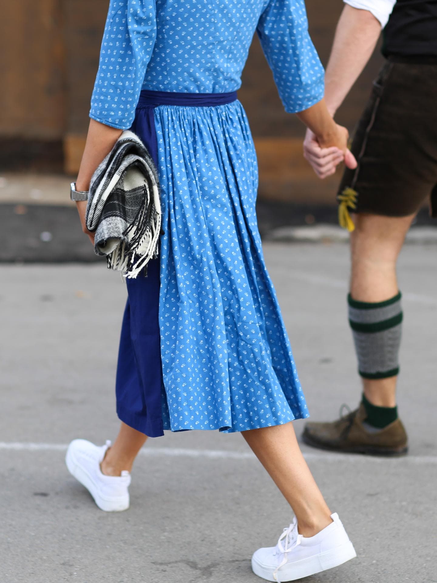 Eine Frau trägt ein Dirndl und weiße Sneaker