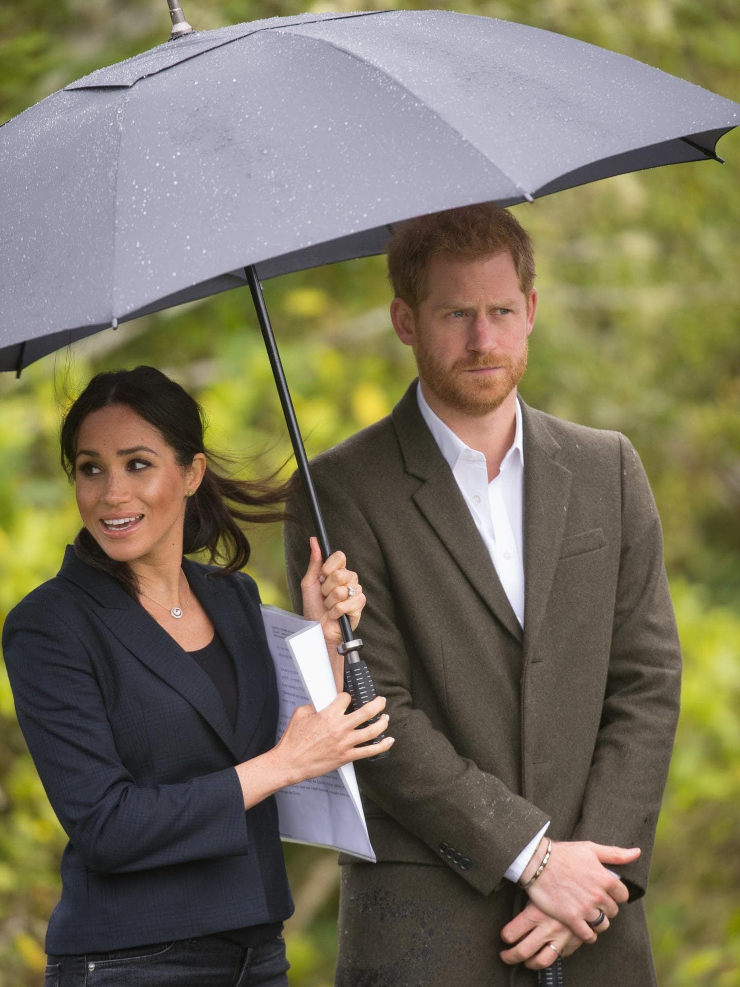 Meghan Markle hält den Regenschirm für Prinz Harry