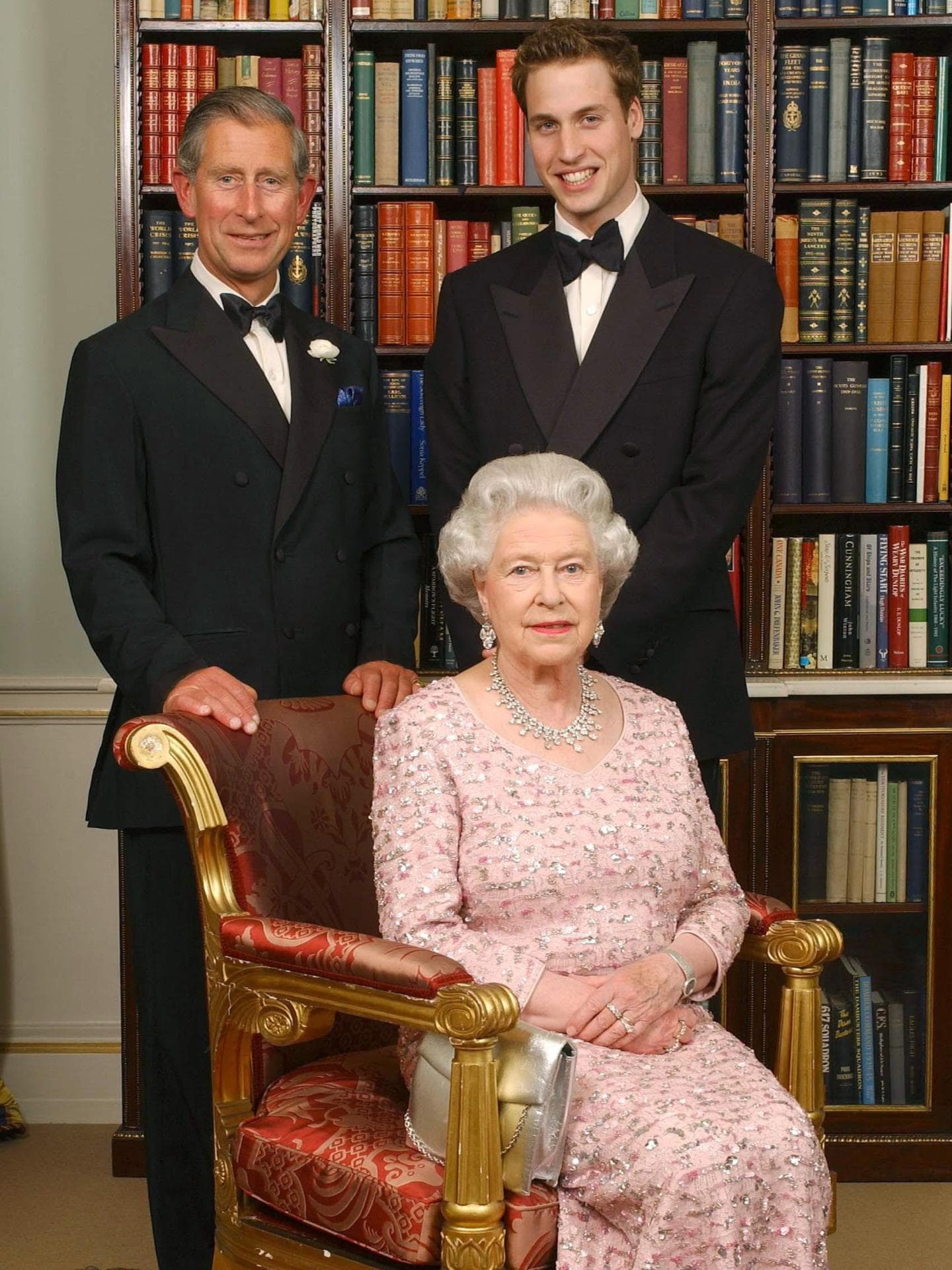 Queen sitzt auf einem Stuhl. Hinter ihr stehen Prinz Chalres und Prinz William