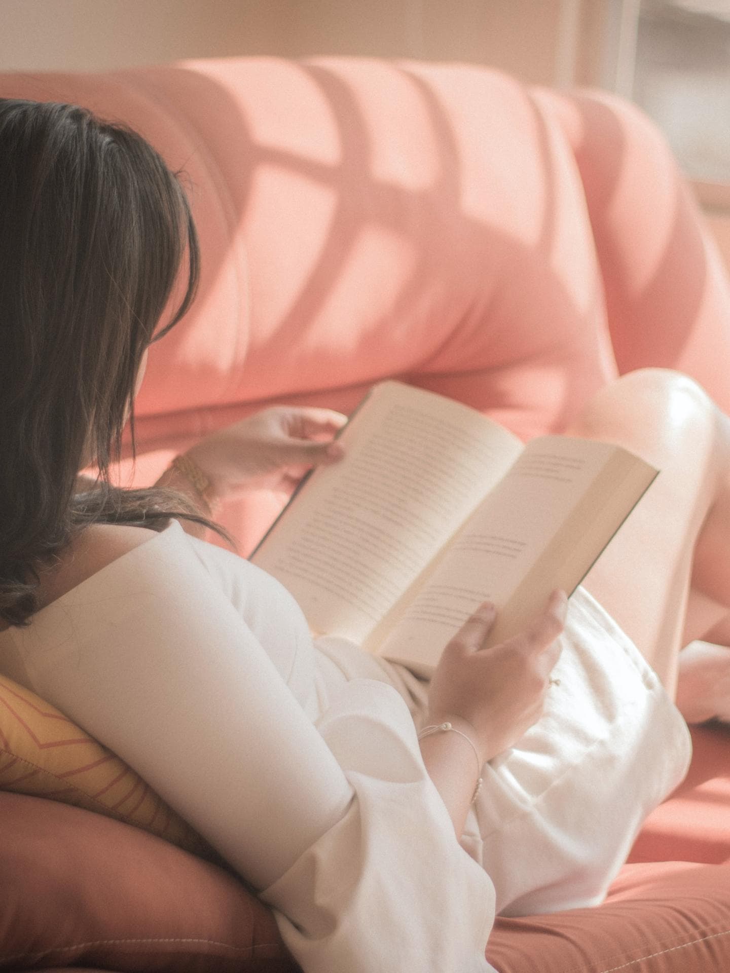 Frau liest Buch auf dem Sofa