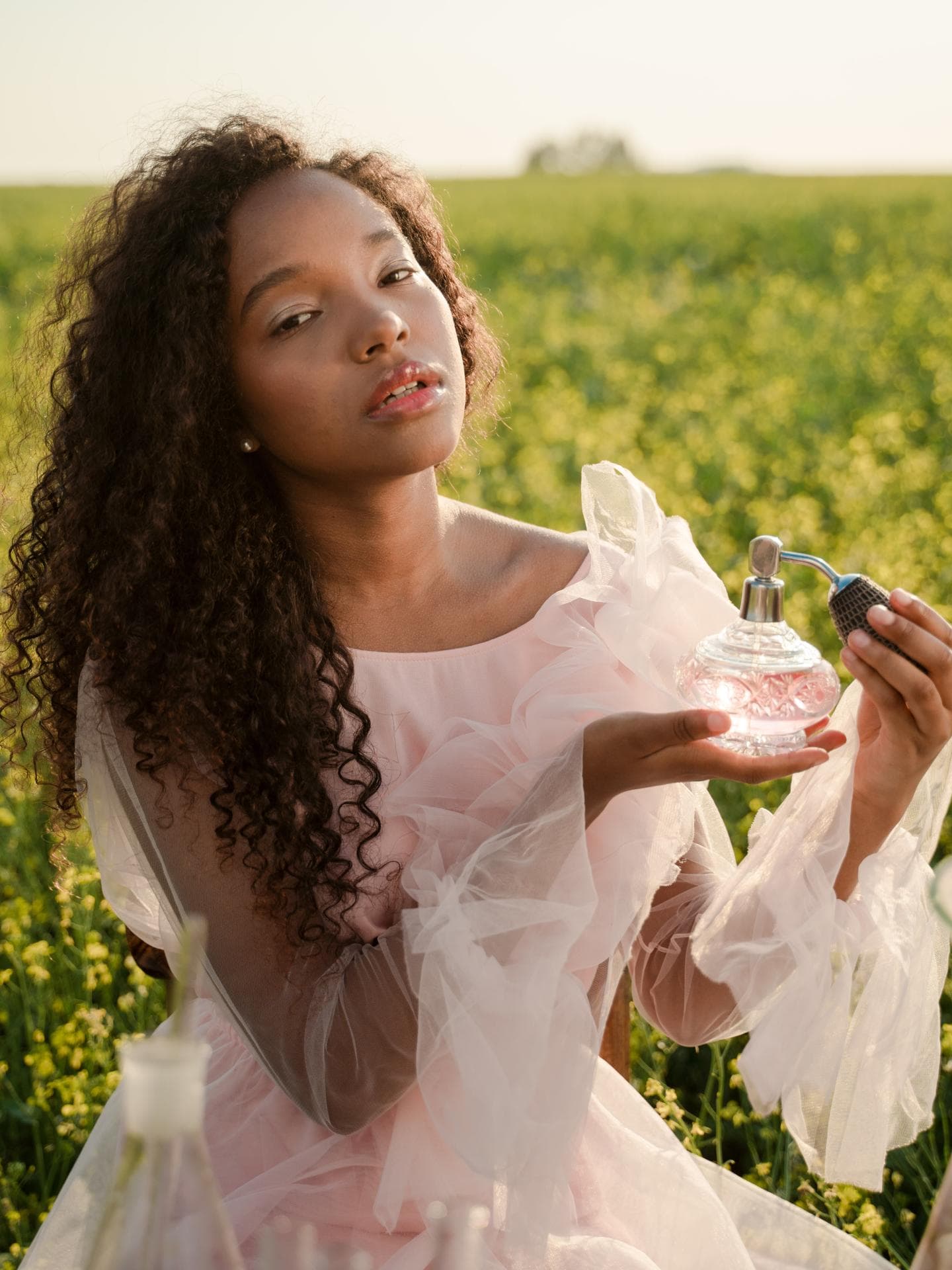 Frau auf Feld mit Parfum in der Hand