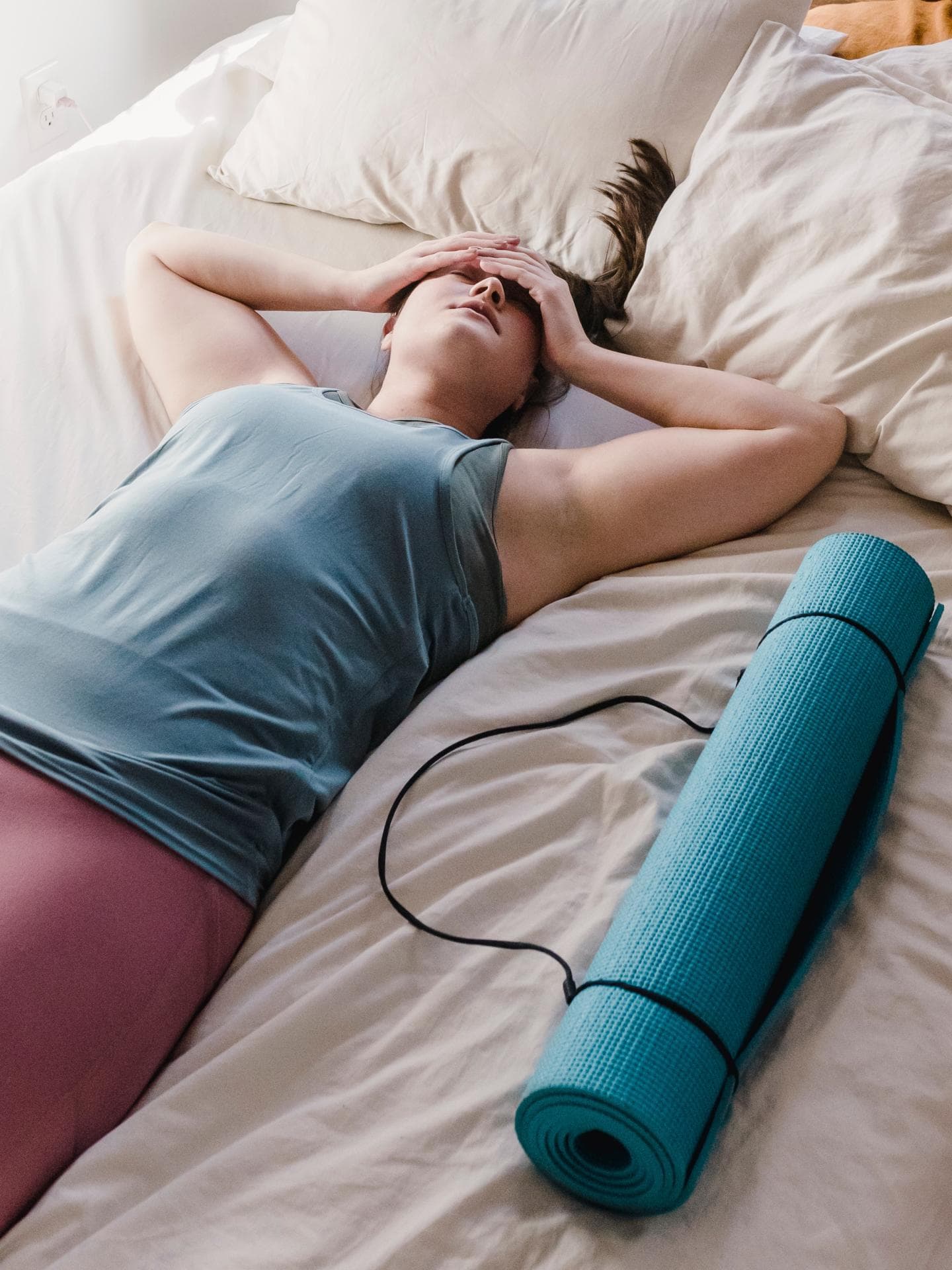 Frau liegt in Sportkleidung auf dem Bett