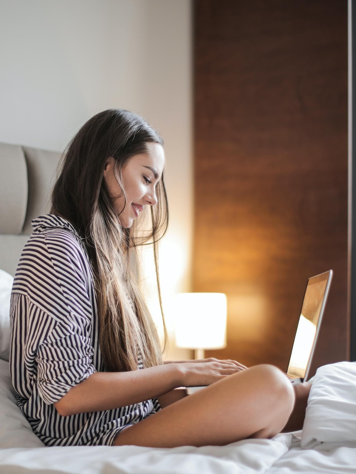 Junge Frau am Laptop im Bett