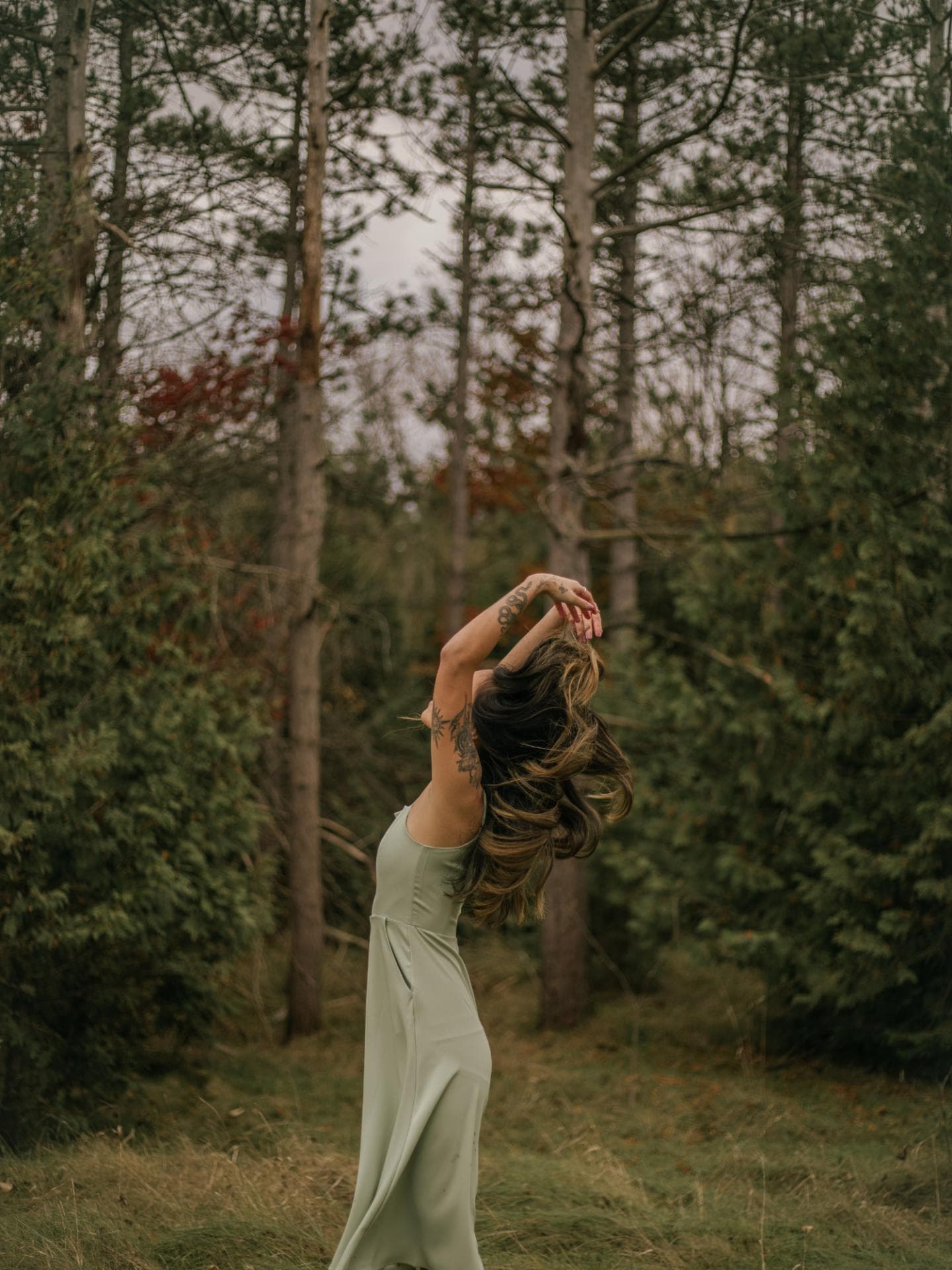 Frau steht in der Natur mit Kleid und Tattoos