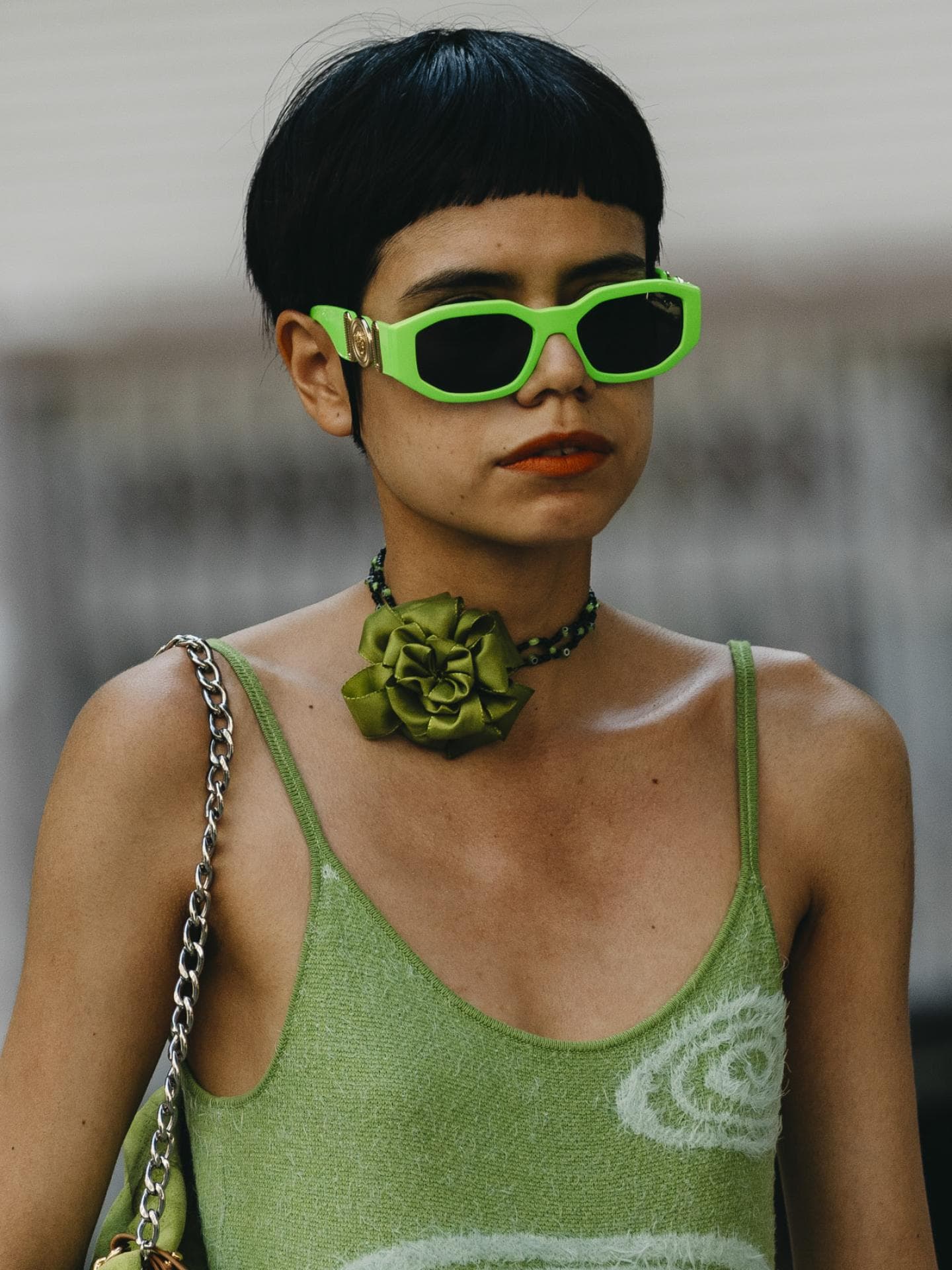 Frau auf Fashion Week trägt grünes Kleid grüne Brille und Micro Pony