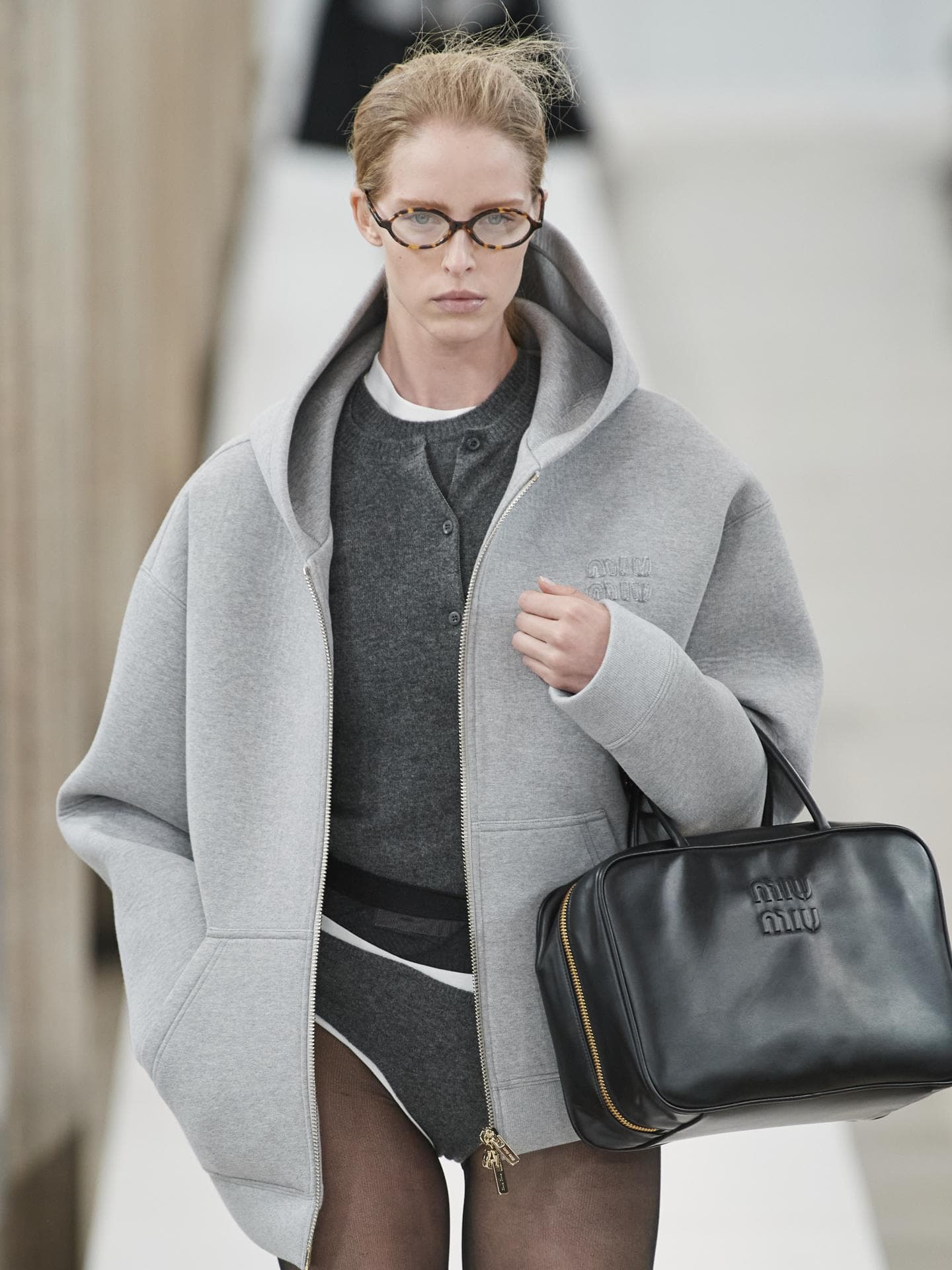 Ein Model trägt eine schmale Brille bei der Miu Miu Herbst Winter 2023 Kollektion