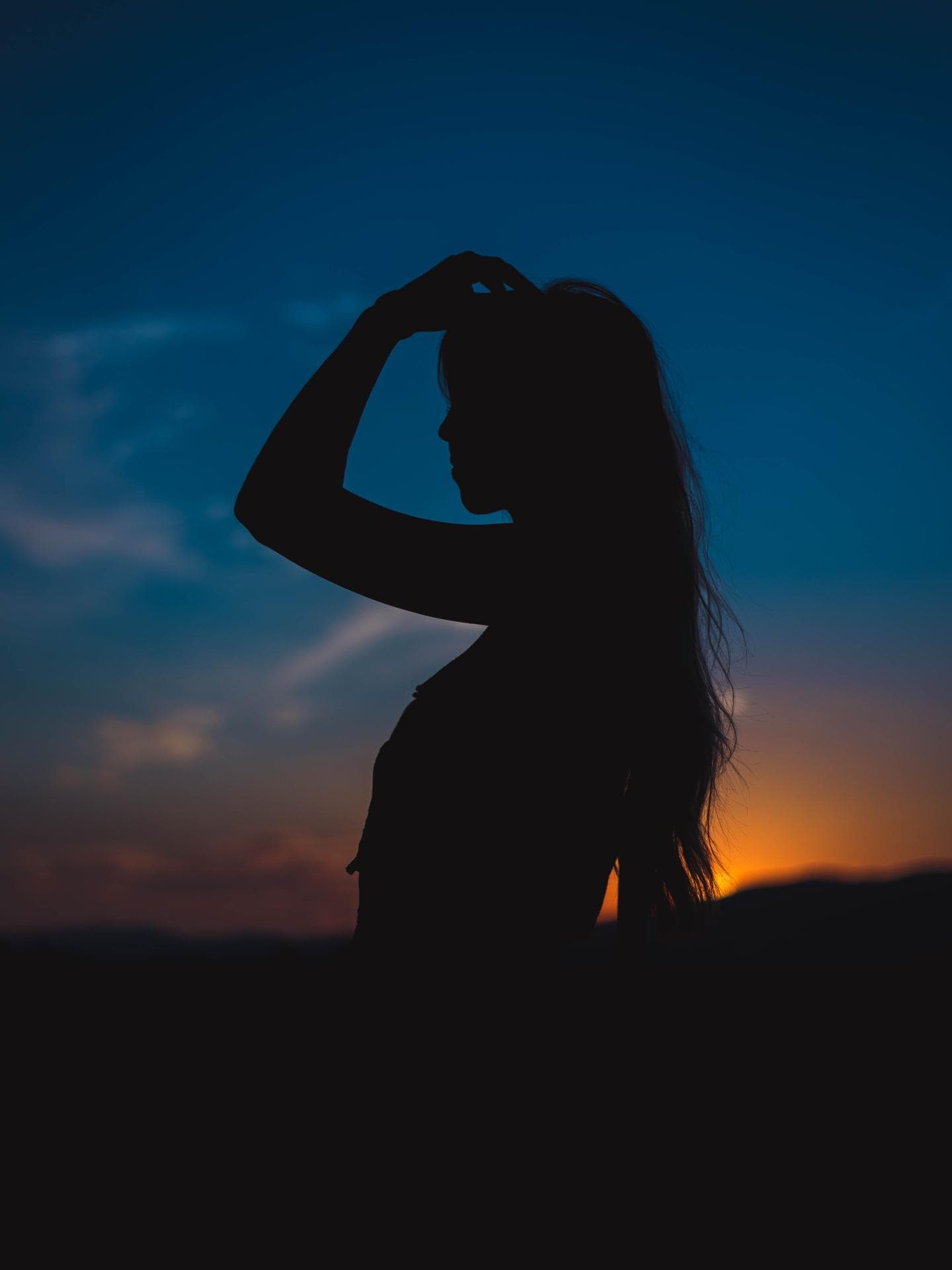 Silhouette einer Frau mit langen Haaren in der Dämmerung