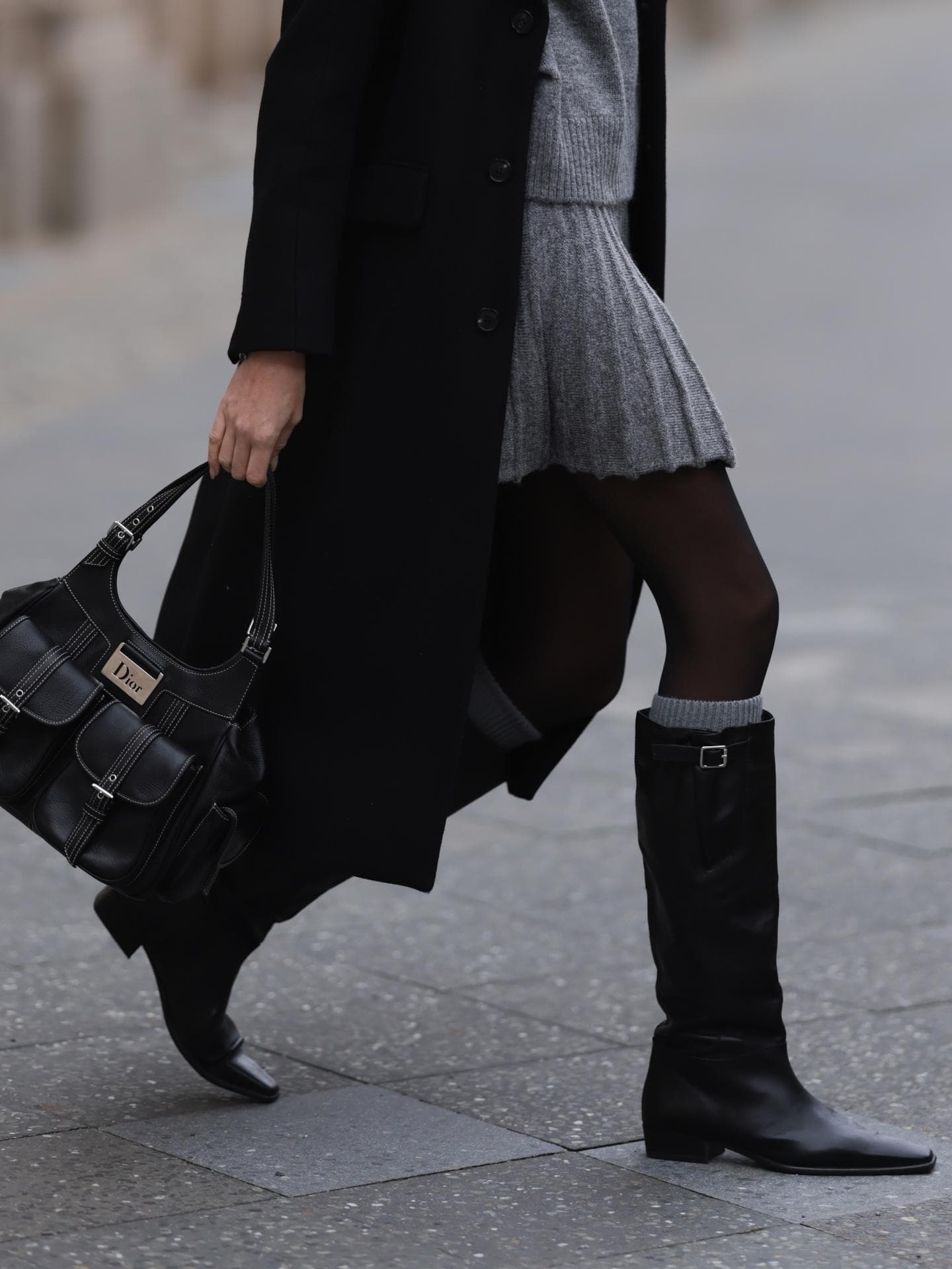 Frau trägt Stiefel und Dior-Tasche