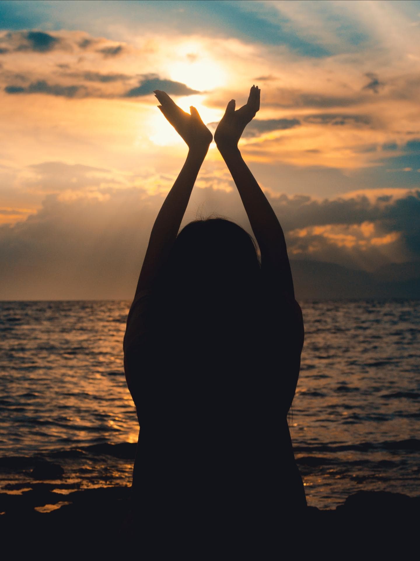 Glücks-Sternzeichen am Wochenende Frau am Meer, die ihre Hände in die Luft streckt