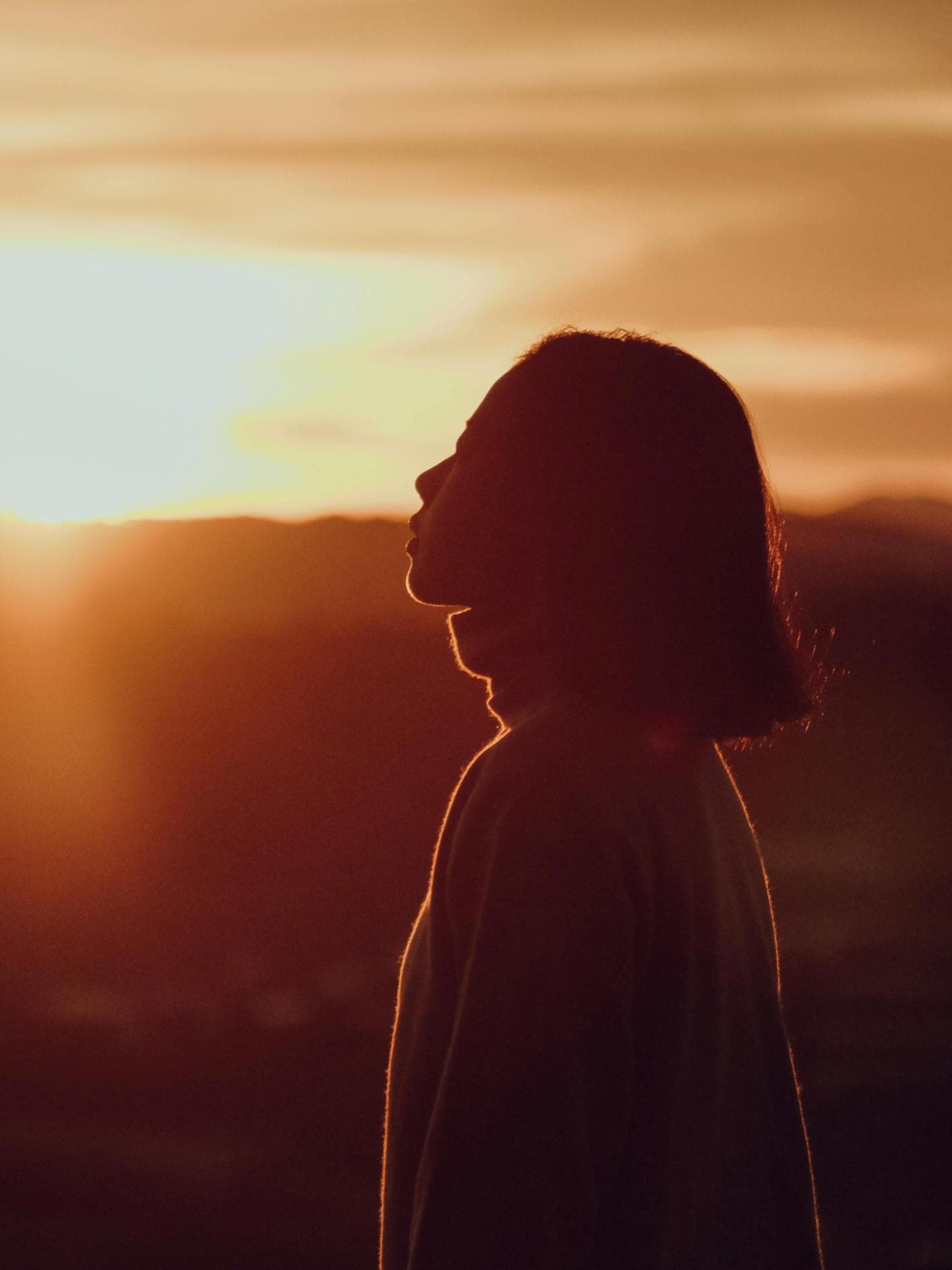 Pech-Sternzeichen am Wochenende Frau mit kurzen Haaren steht vor einem Sonnenuntergang