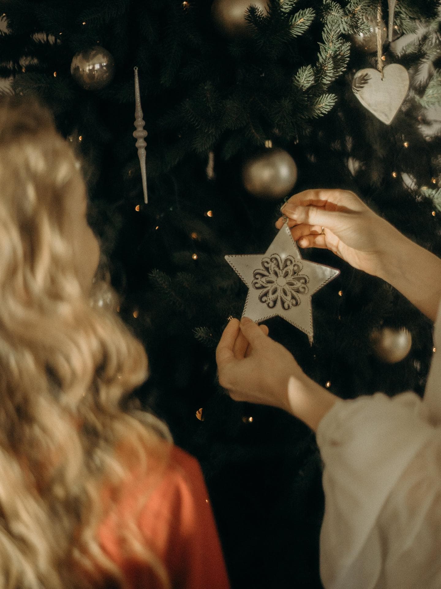Weihnachtshoroskop Herausforderungen Frauen schmücken Weihnachtsbaum mit Stern