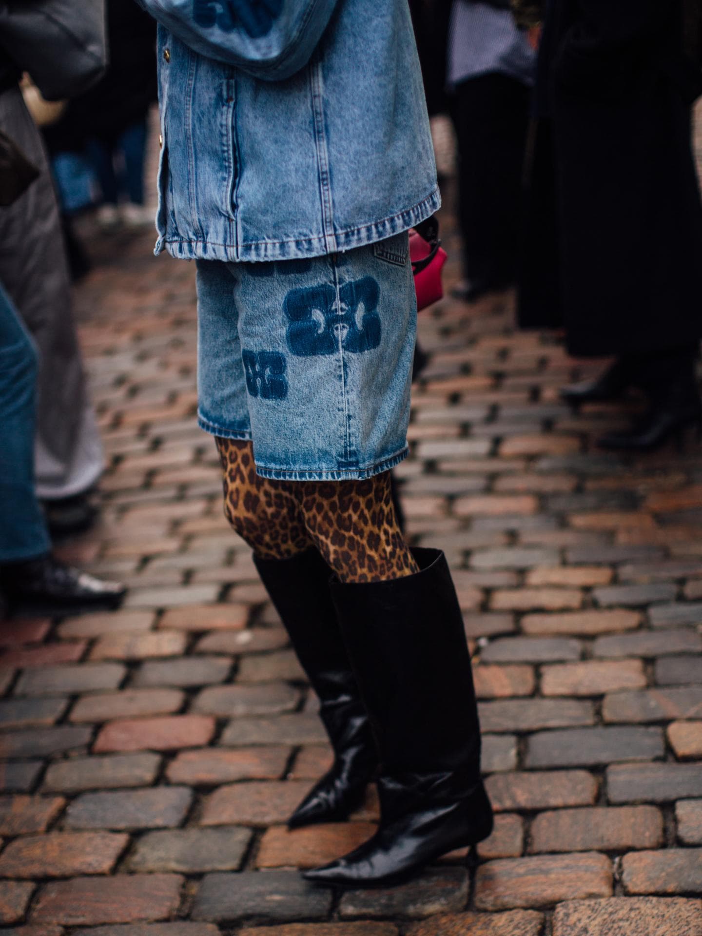 Frau trägt auf Copenhagen Fashion Week Jeans Kombi und Leomuster Strumpfhose und spitze schwarze Stiefel Frau trägt auf Copenhagen Fashion Week Jeans Kombi und Leomuster Strumpfhose und spitze schwarze Stiefel