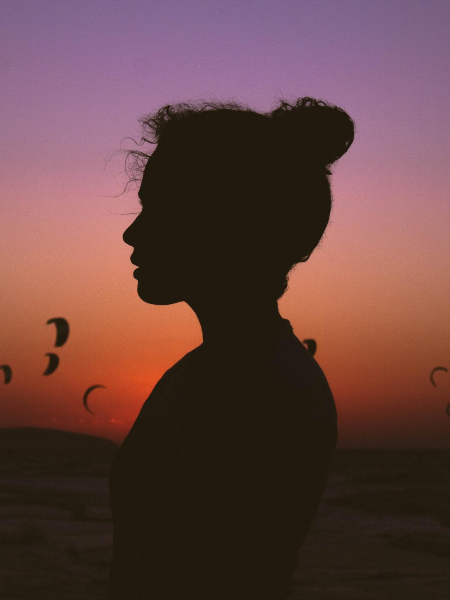 Frau mit Dutt steht vor einem Sonnenuntergang