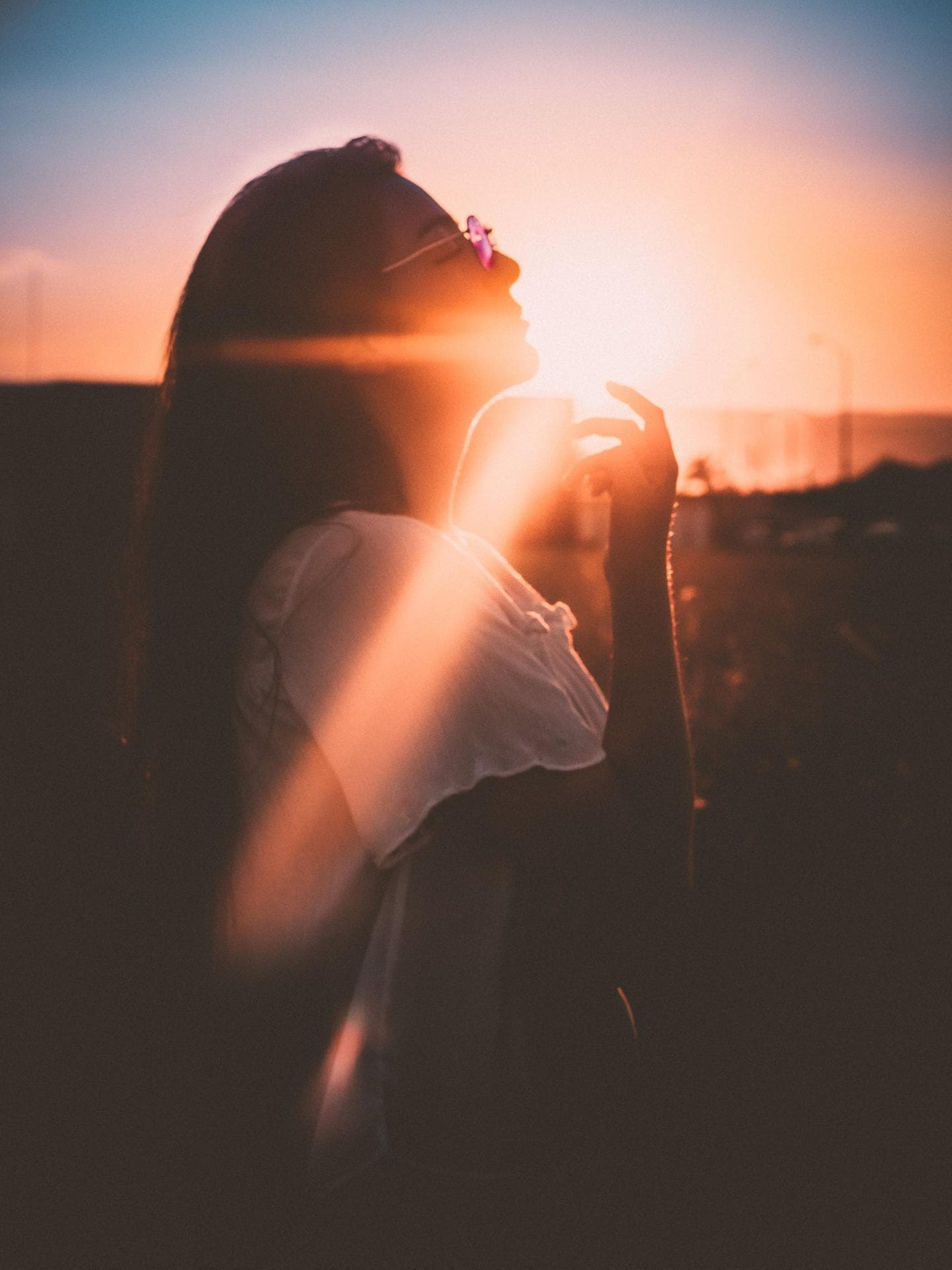 Glücks-Sternzeichen der Woche Frau mit langen Haaren und Brille beim Sonnenuntergang