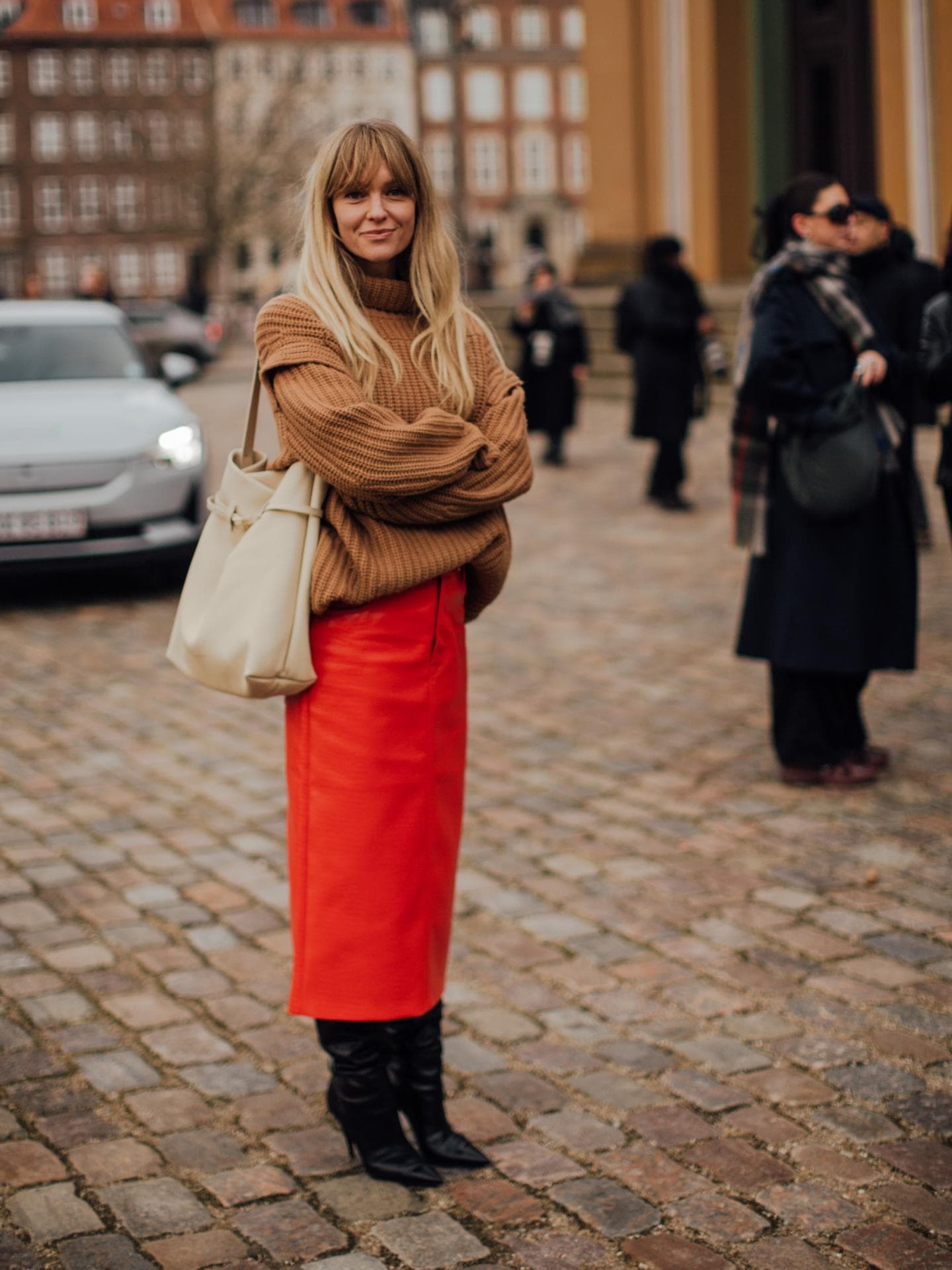Frau trägt auf Kopenhagen Fashion Week roten Rock in Midi-Länge und kniehohe Stiefel Frau trägt auf Kopenhagen Fashion Week roten Rock in Midi-Länge und kniehohe Stiefel