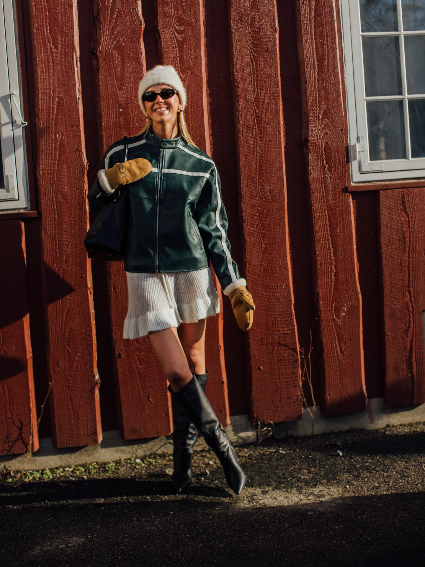 Frau trägt auf Kopenhagen Fashion Week schwarze Lederjacke, cremefarbenen Strickrock und kniehohe Stiefel Frau trägt auf Kopenhagen Fashion Week schwarze Lederjacke, cremefarbenen Strickrock und kniehohe Stiefel