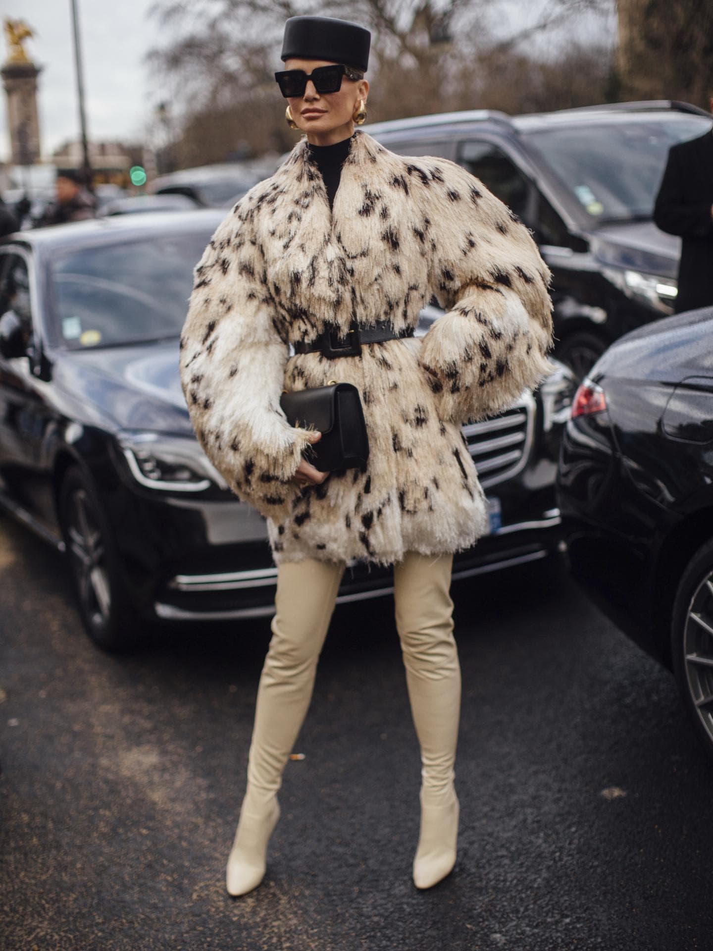 Frau trägt auf Paris Fashion Week Fake Fur Mantel XXL Hut und Sonnenbrille plus beigefarbene Overknees
