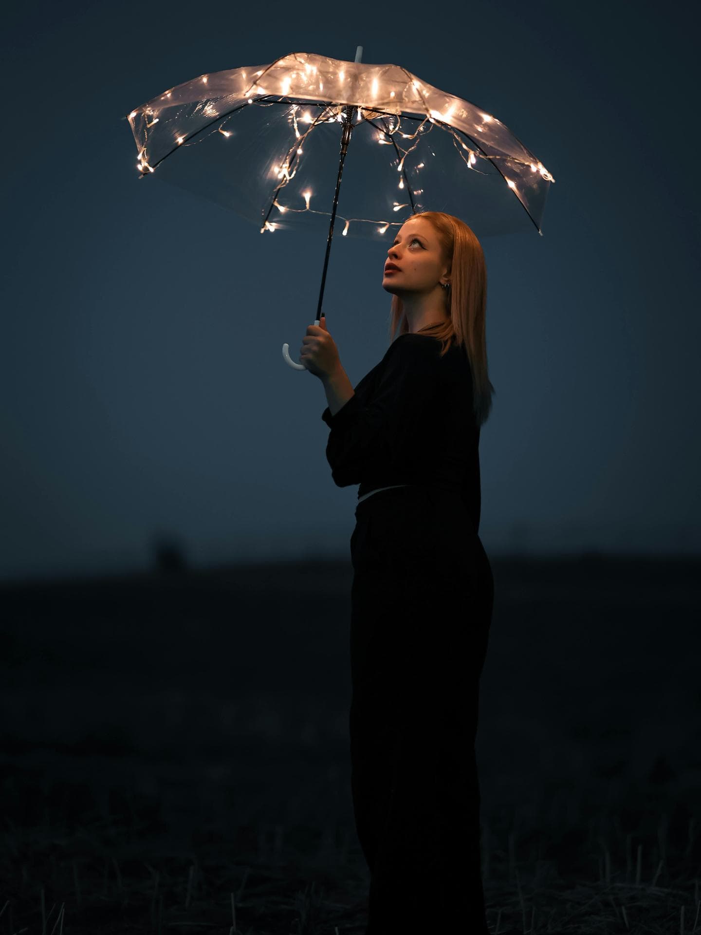 Frau hält einen Regenschirm mit Lichterketten in der Hand