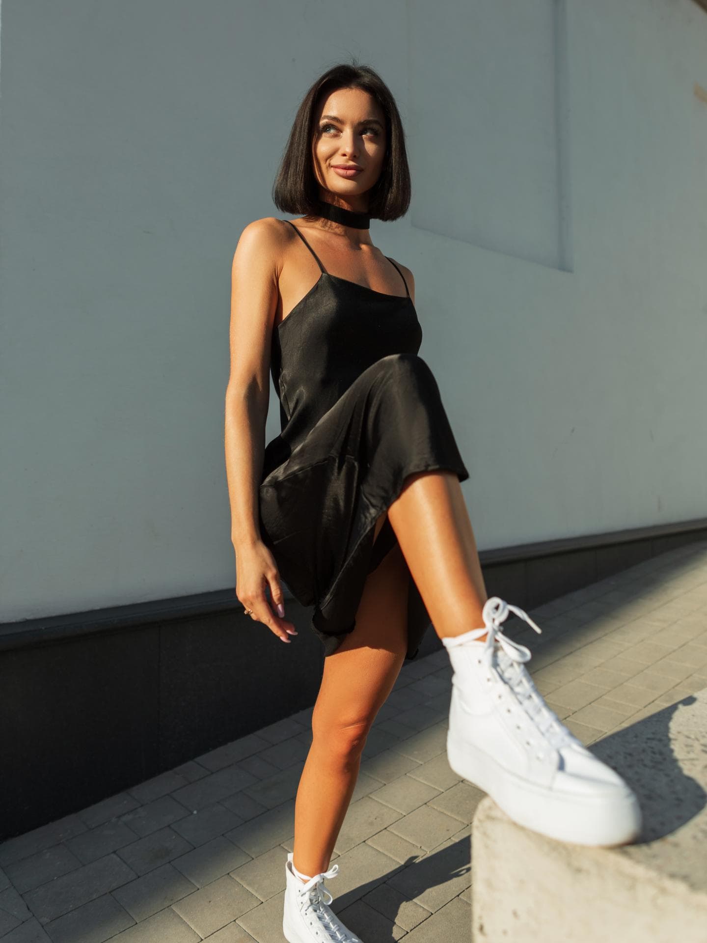 Frau in schwarzem Kleid mit weißen Sneakers Frau in schwarzem Kleid mit weißen Sneakers