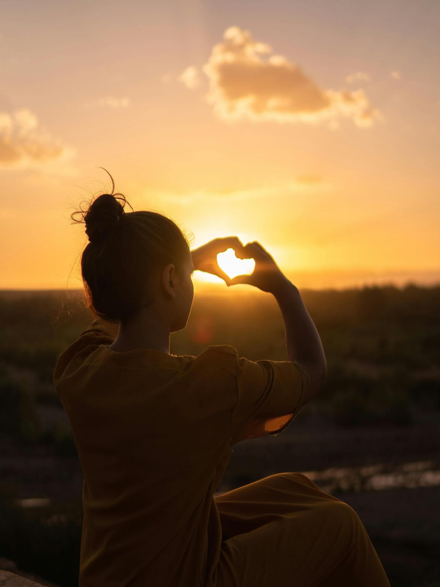 Sternzeichen, die heimlich verliebt sind Frau macht Herz mit Händen vor Sonnenuntergang