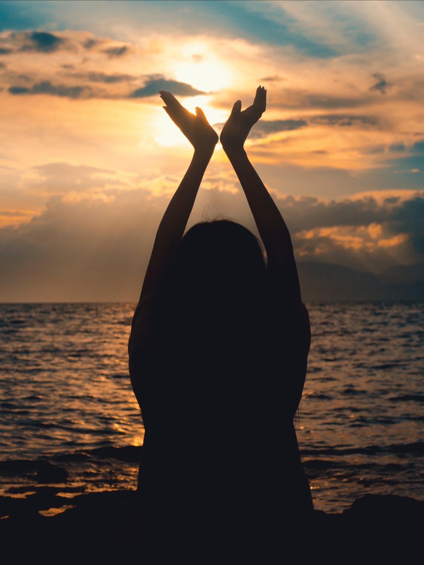 Wochenendhoroskop Glück Silhouette einer Frau am Strand mit dem Meer im Hintergrund