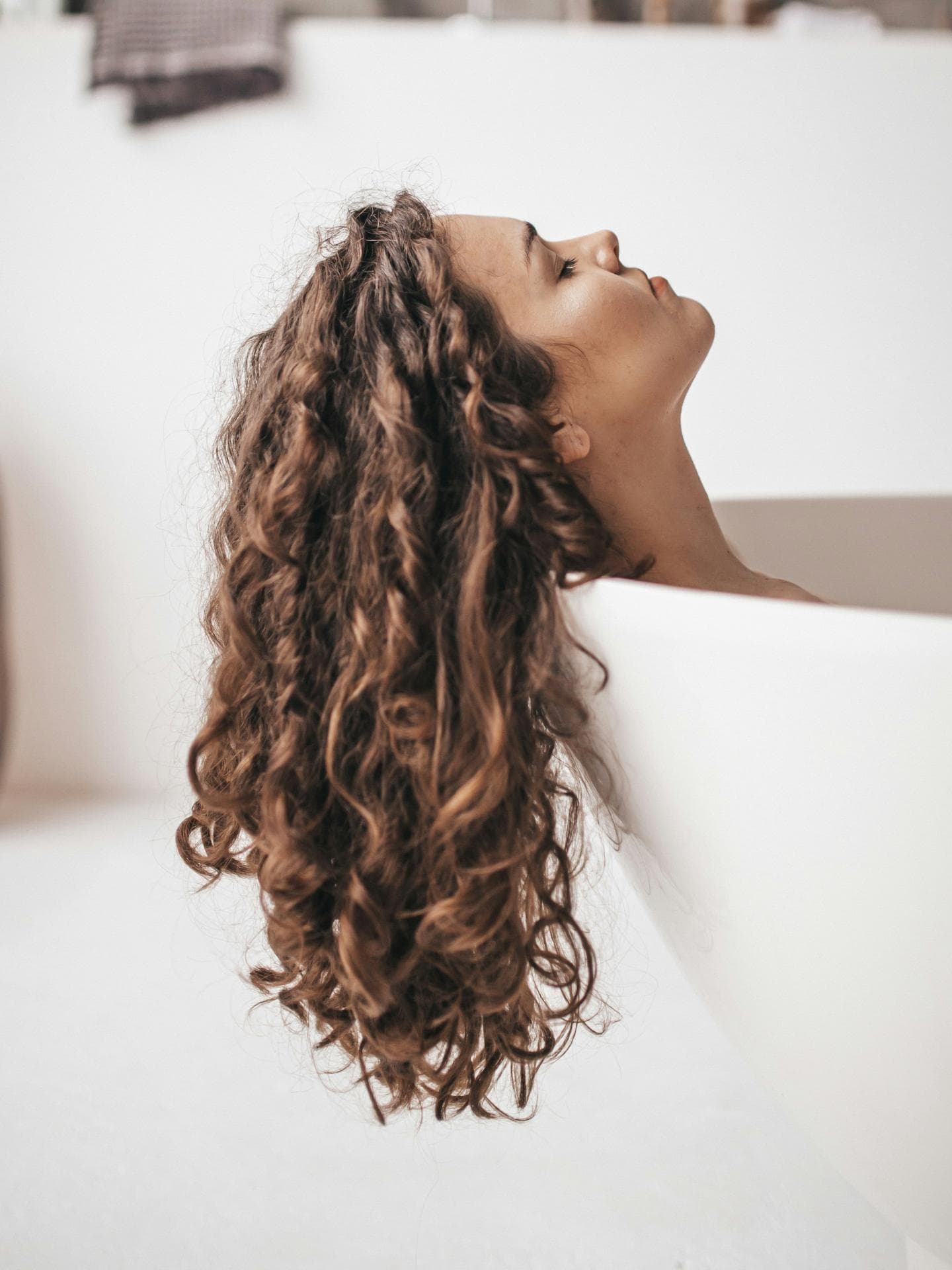 Dicke Haare: Frau liegt in Wanne mit braunen Locken