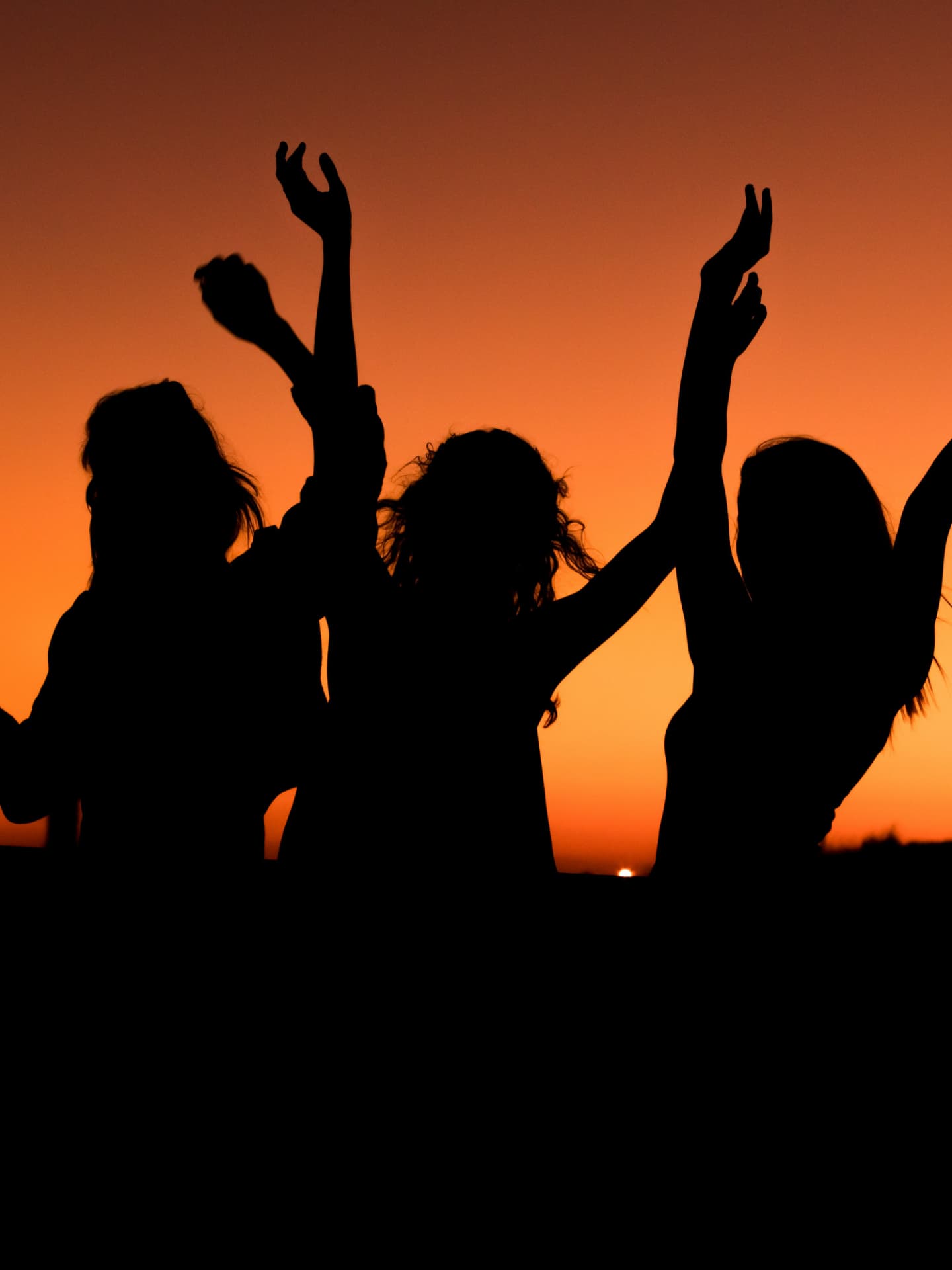 Drei Frauen tanzen unter dem Abendhimmel