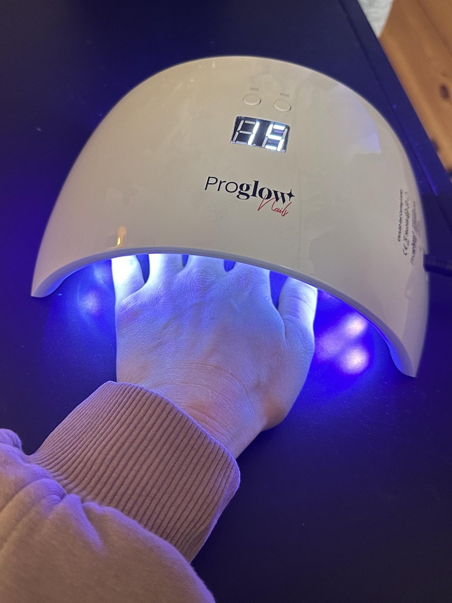 Unter der UV-Lampe wird der Lack ausgehärtet. Die Hand wird unter die UV-Lampe von Proglow gehalten.