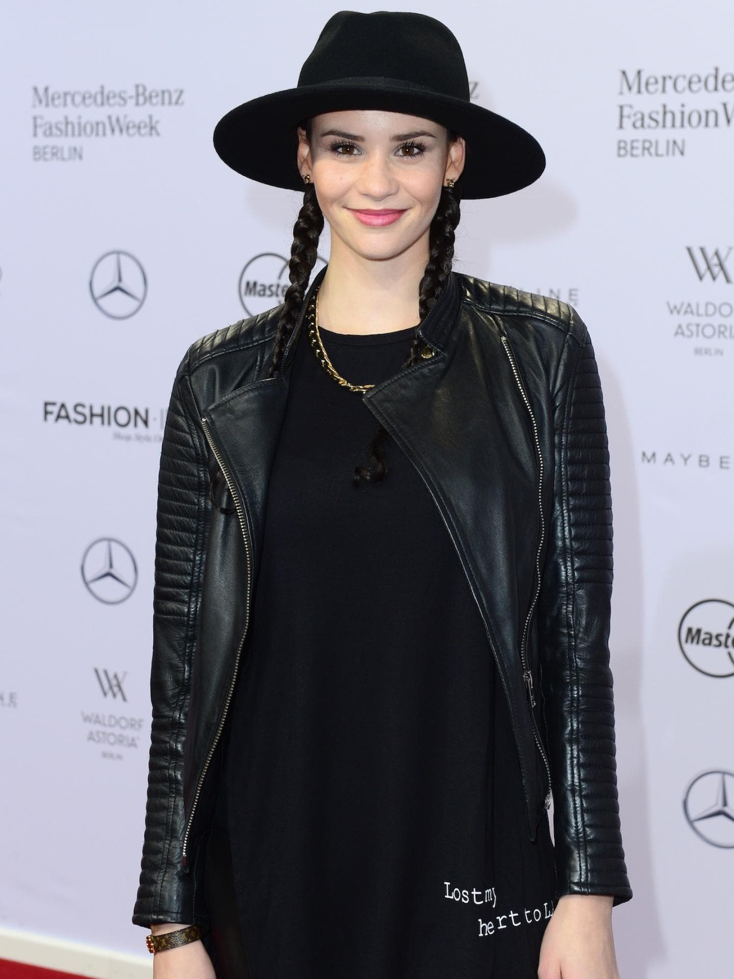 Betty Taube spielte nach der GNTM-Zeit mit vielen Accessoires. Betty Taube mit einem schwarzen Oberteil und Lederjacke und Hut auf dem Roten Teppich.