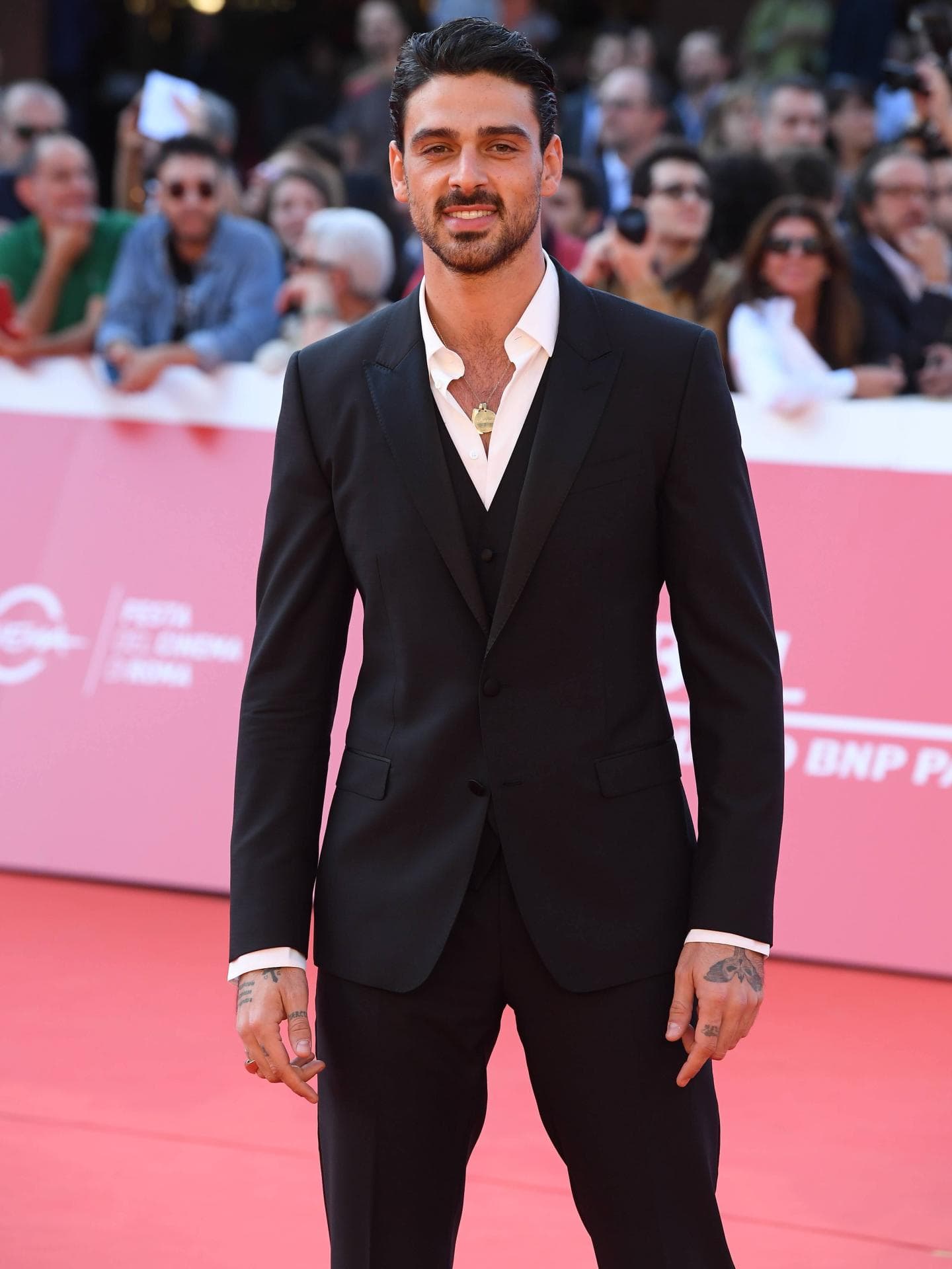 Beim Rome Film Festival 2019 machte Michele Morrone noch einen jüngeren Eindruck. Michele Morrone auf dem roten Teppich mit einem schwarzen Anzug und einer goldenen Kette mit Anhänger.