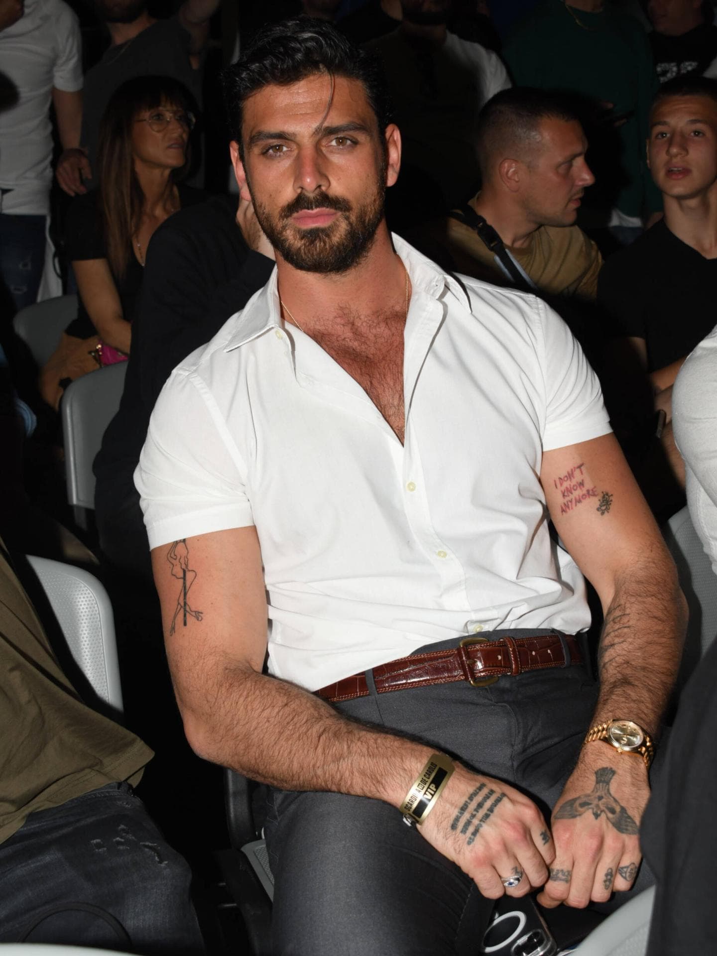 Michele Morrone ist heute auch bekannt für seine Tattoos. Michele Morrone mit einem weißen, kurzärmligen Hemd und einigen Tattoos an den Armen.