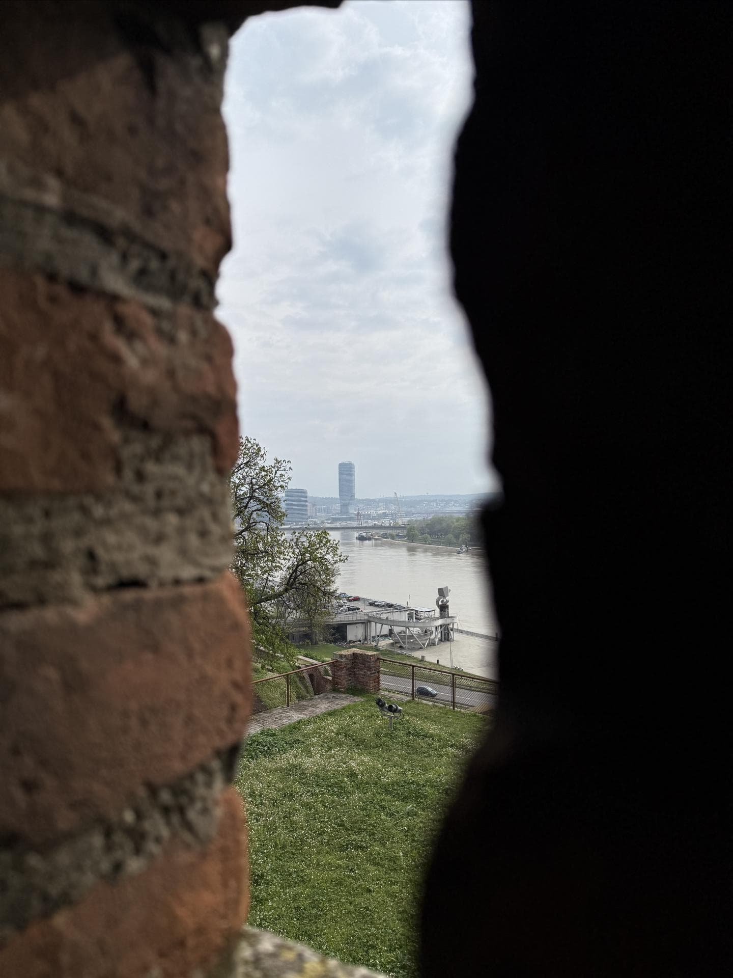 Ein Blick durch einen Mauerspalt auf einen Fluss und die Waterfront in Belgrad.