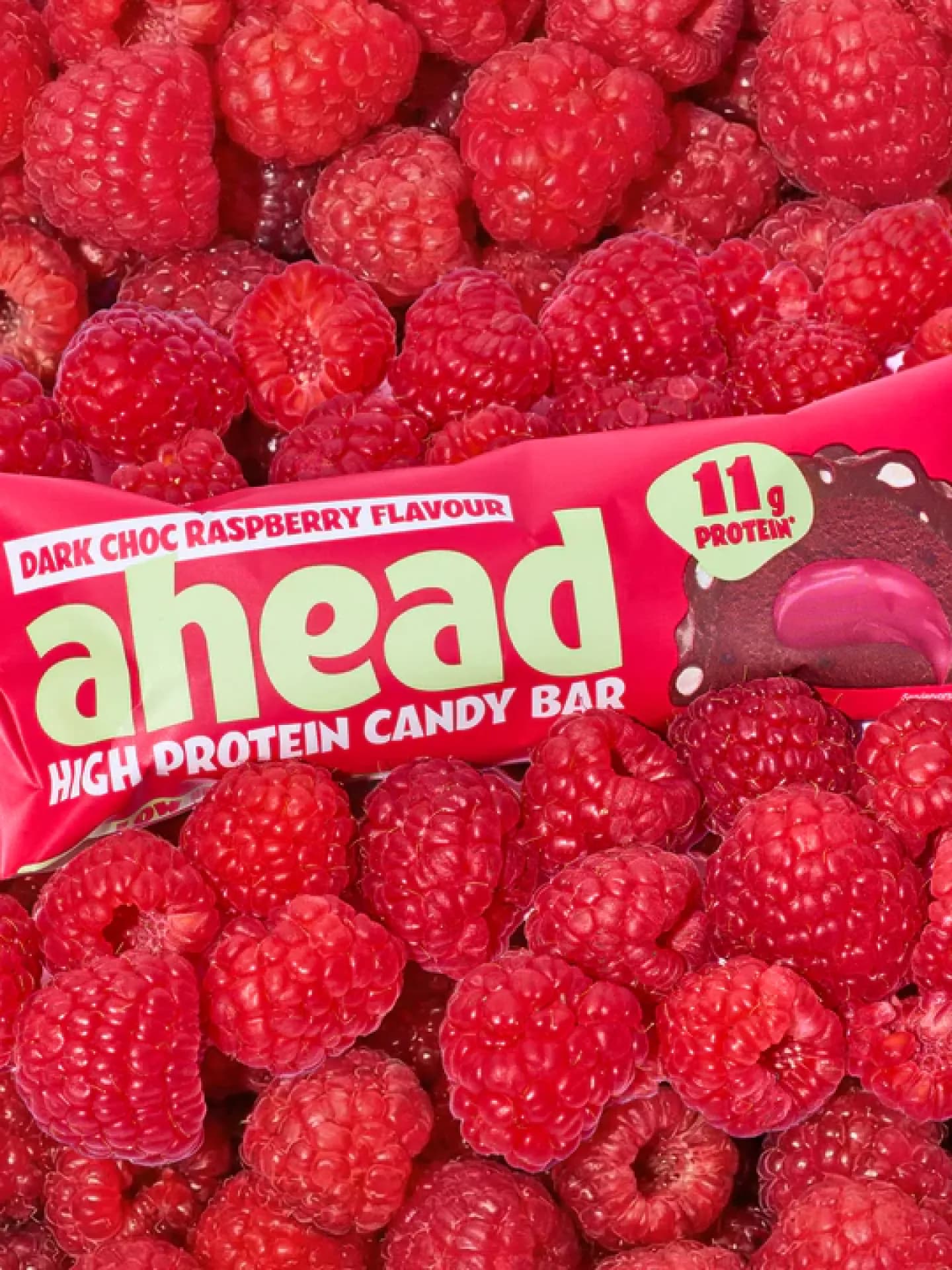Dark Chocolate Raspberry High Protein Candy Bar von Ahead liegt auf Himbeeren.