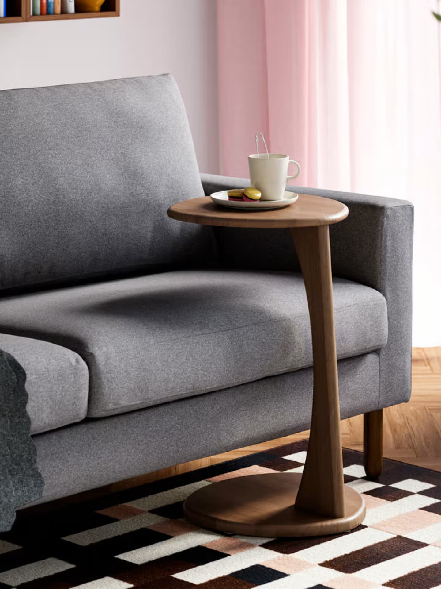 Ein kleiner Beistelltisch kann prima an das Sofa rangeschoben werden. Ein graues Sofa mit einem dunkelbraunen Beistelltisch.