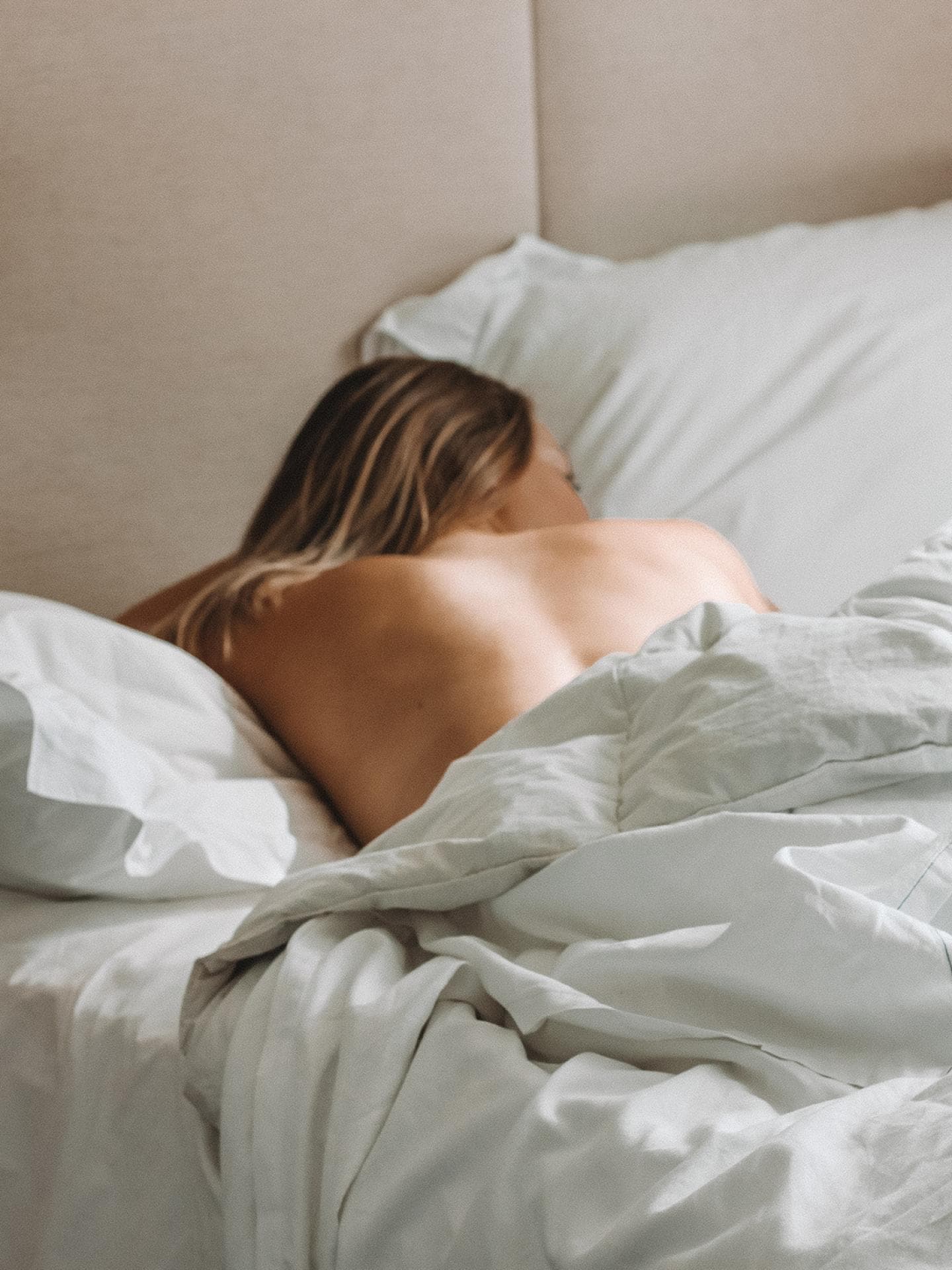 Frau liegt unbekleidet im Bett