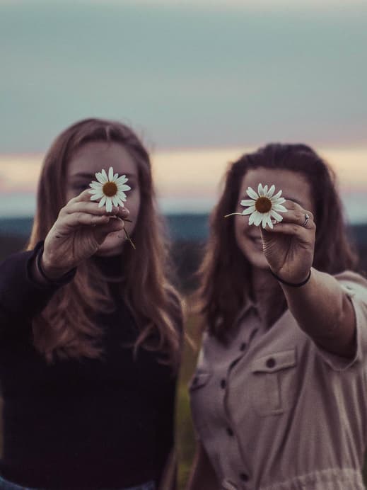 Zwei Frauen halten Blume in die Kamera