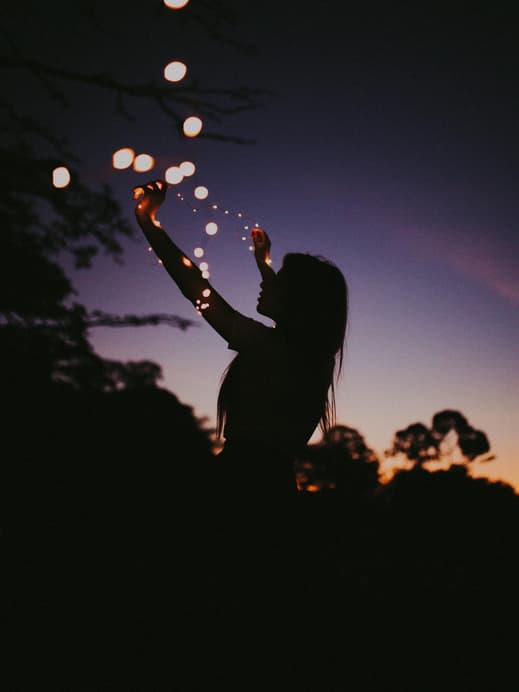 Silhouette einer Frau mit einer Lichterkette um den Arm