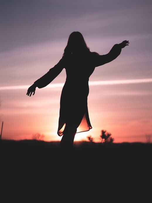 Silhouette einer Frau im Kleid während eines Sonnenuntergangs