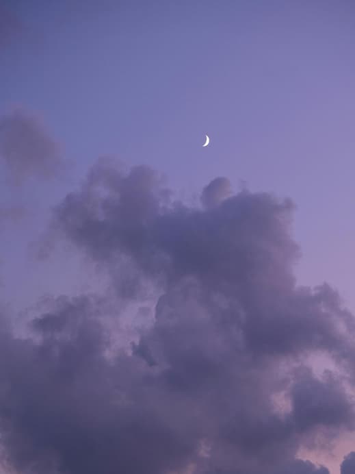 Halbmond am lilafarbenen Himmel mit Wolken