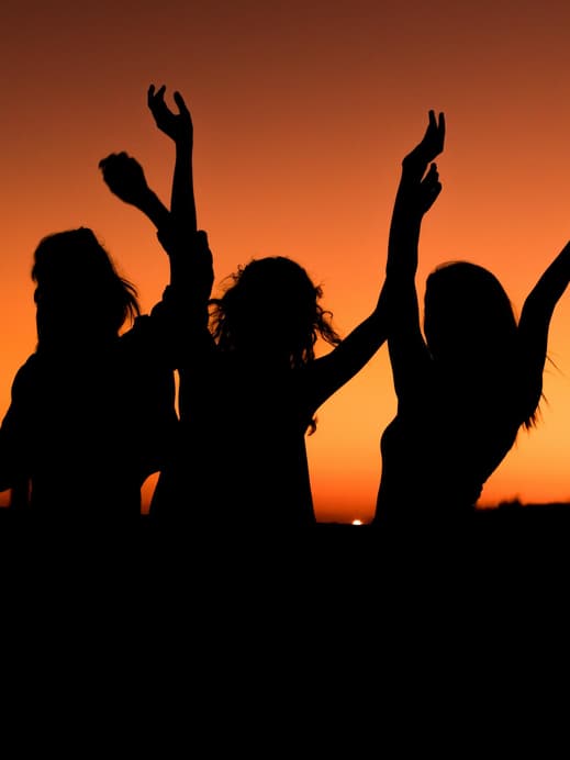 Drei Silhouetten von Frauen vor Sonnenuntergang